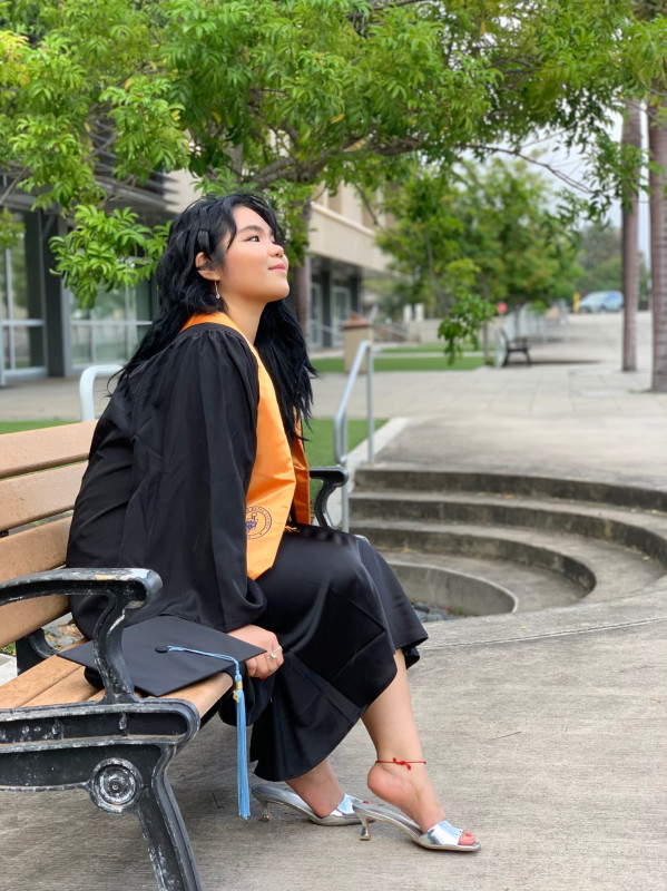 She is sitting down on the bench with her head up smiling