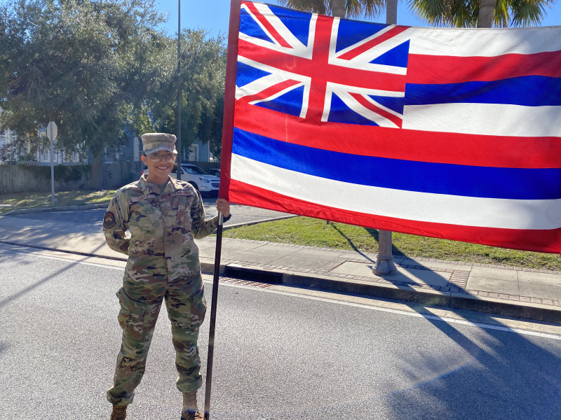 Picture of Toni in her military uniform holding a Hawaiian flag