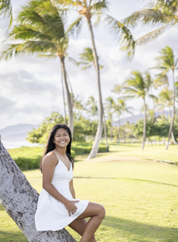 In white dress leaning on a tree at the beach