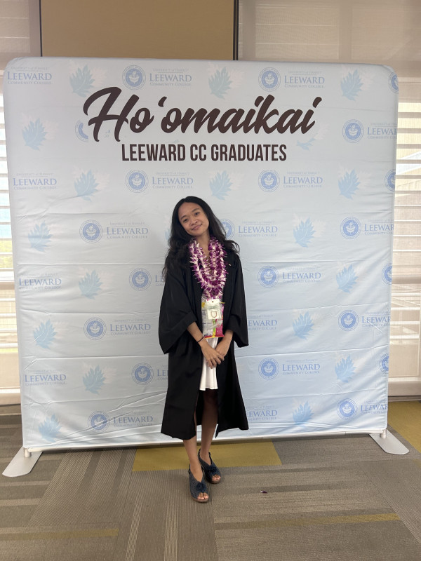Picture of Princess Cyrile Butac in cap and gown, in front of commencement backdrop