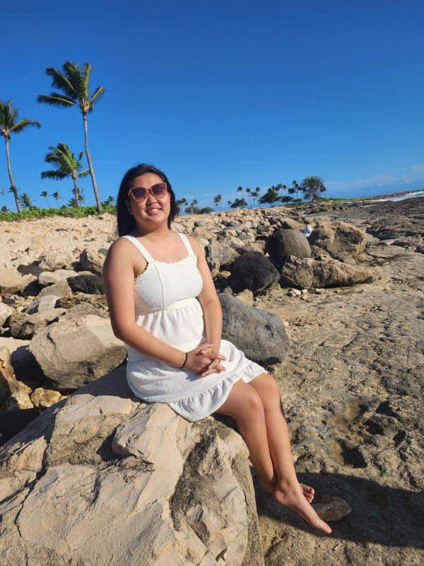 I'm sitting on a rock at beach, wearing a white dress and sun glasses. Its a very sunny day