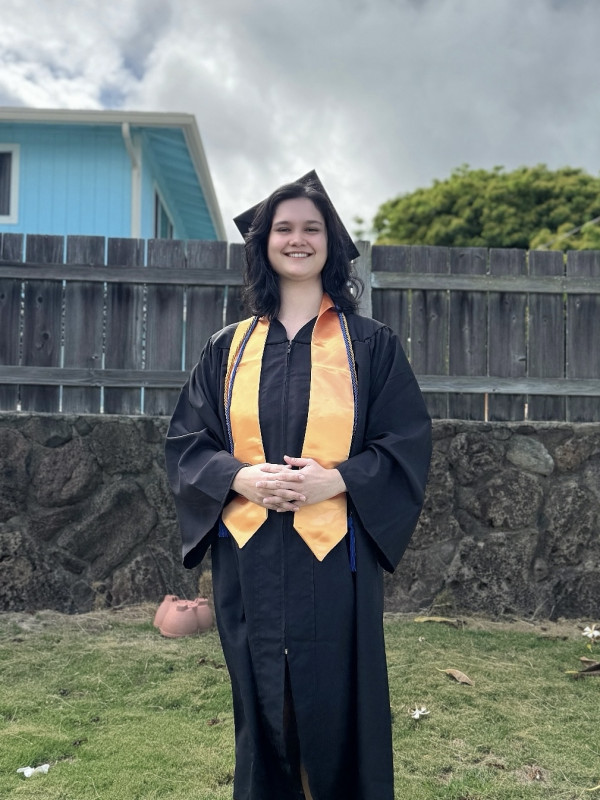 Anna Breimon wearing cap and gown with arms posed in front of body.